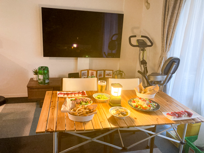 自宅に木製のテーブルを広げて料理を配置している画像